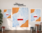A poster, paper print, and a rolled-out canvas version of the "Tainted Vision" art piece —are displayed side by side on a white wall next to an open window with a curtain on the left-hand side, a plant, paint cans, and the company logo positioned above the artwork display.