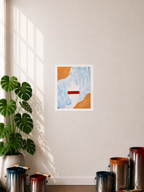 A Paper Print featuring a mixed media art piece displayed hanging on a wall in a room with a plant, paint cans, and window shadows in the display. The art image has a blue and white limewash background with gold textured way like accents on the upper left corner and the lower right corner of the piece. It also features a white head to lower shoulder silhouette of a person made up of a depicted texture like pattern that has a red paint brush streak that lays over the eyes to ears.
